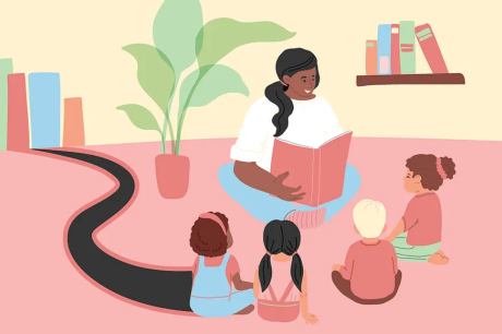 An adult is smiling and reading a book to a group of children who are sitting down.